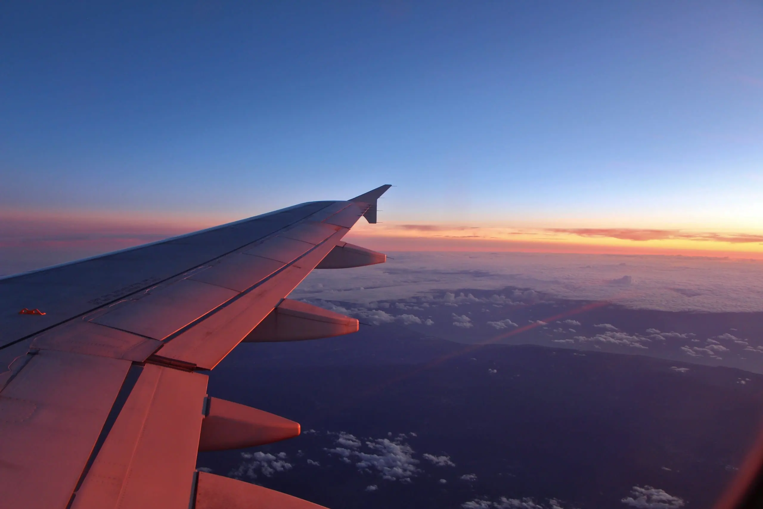 An aircraft wing above the clouds at sunset