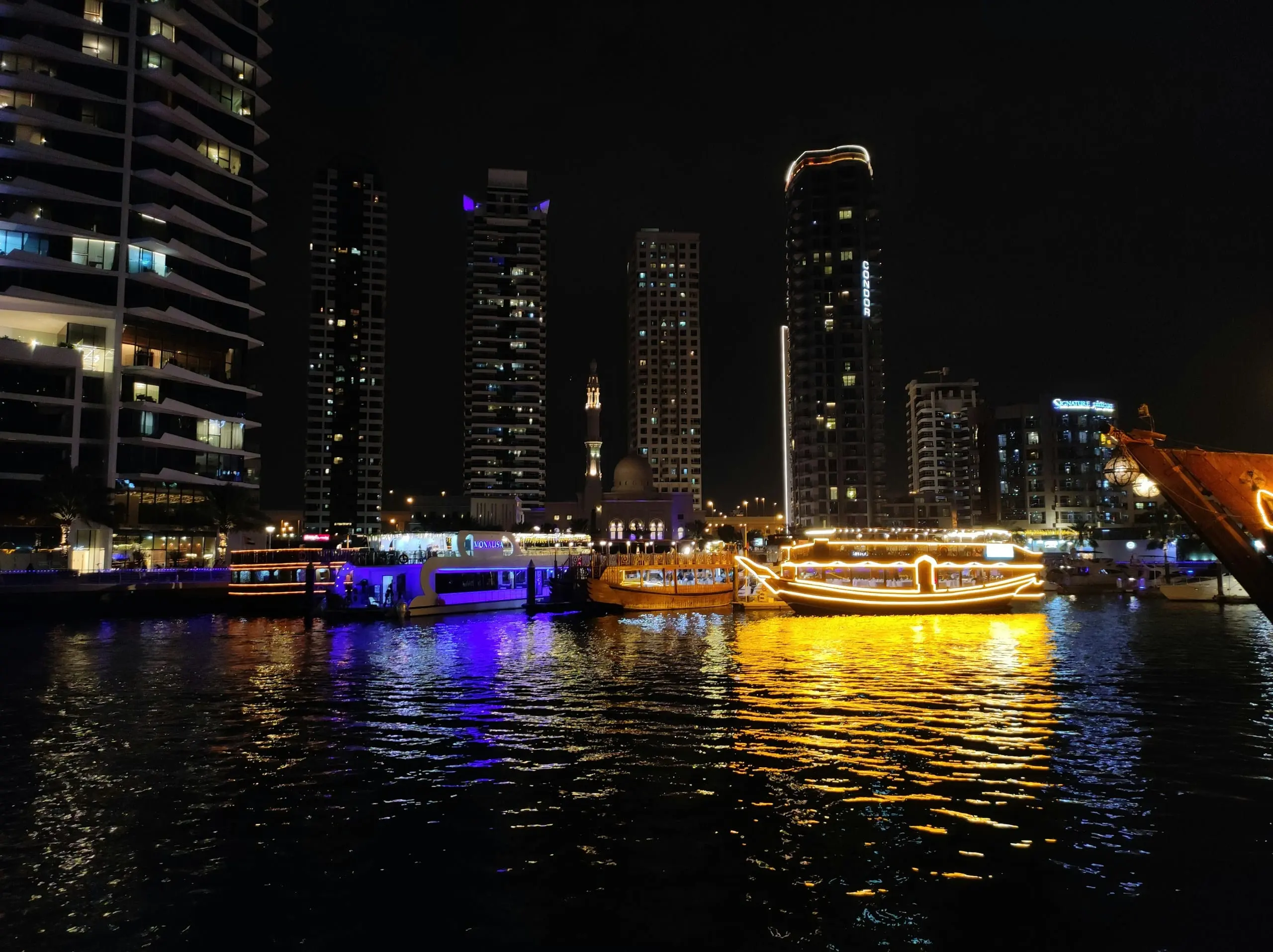 Illuminated dhow cruise boats on the water at night