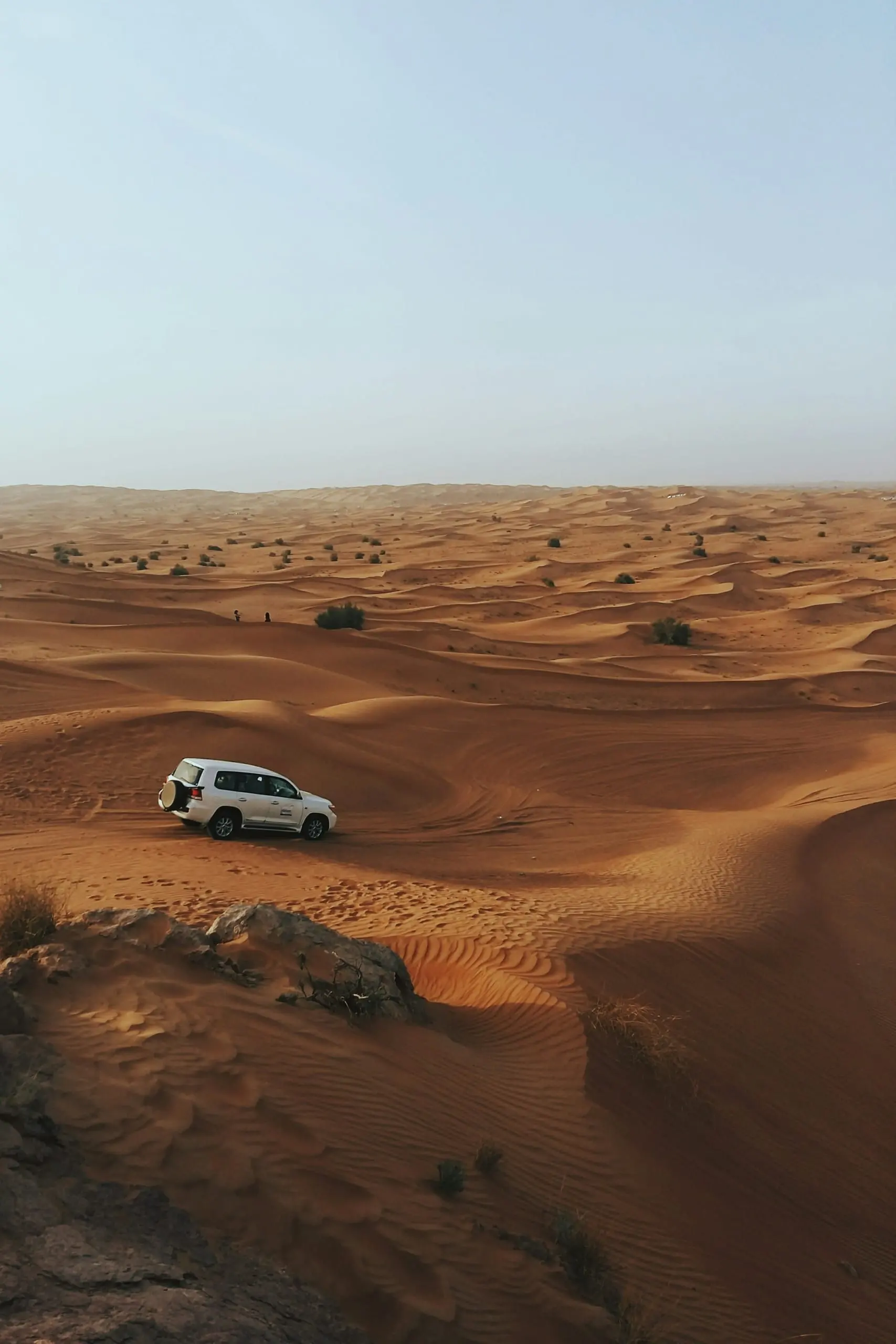 A 4x4 crossing rolling red dunes on a desert safari
