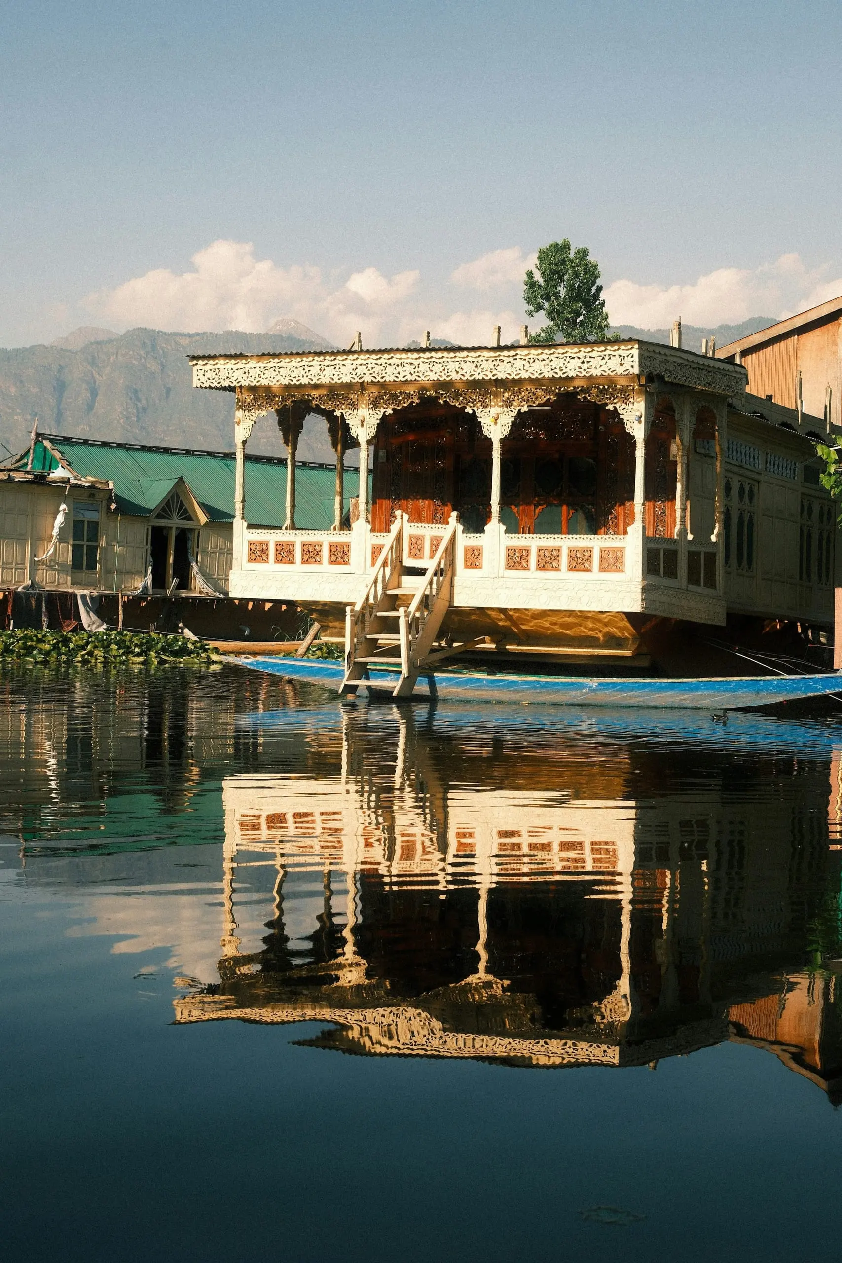 An intricately carved houseboat reflected in the calm waters of Dal Lake