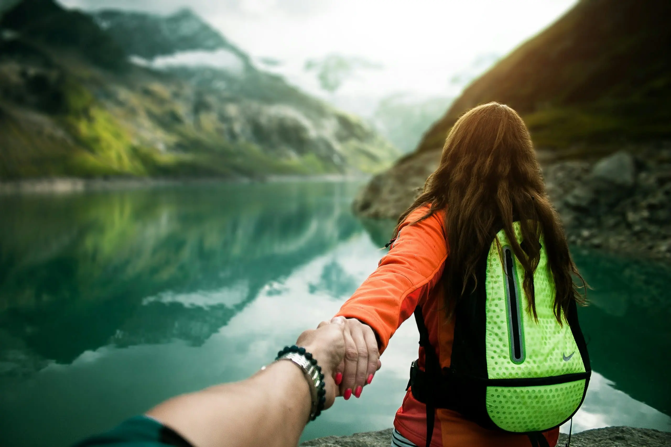 A traveller leading the way towards a mountain lake